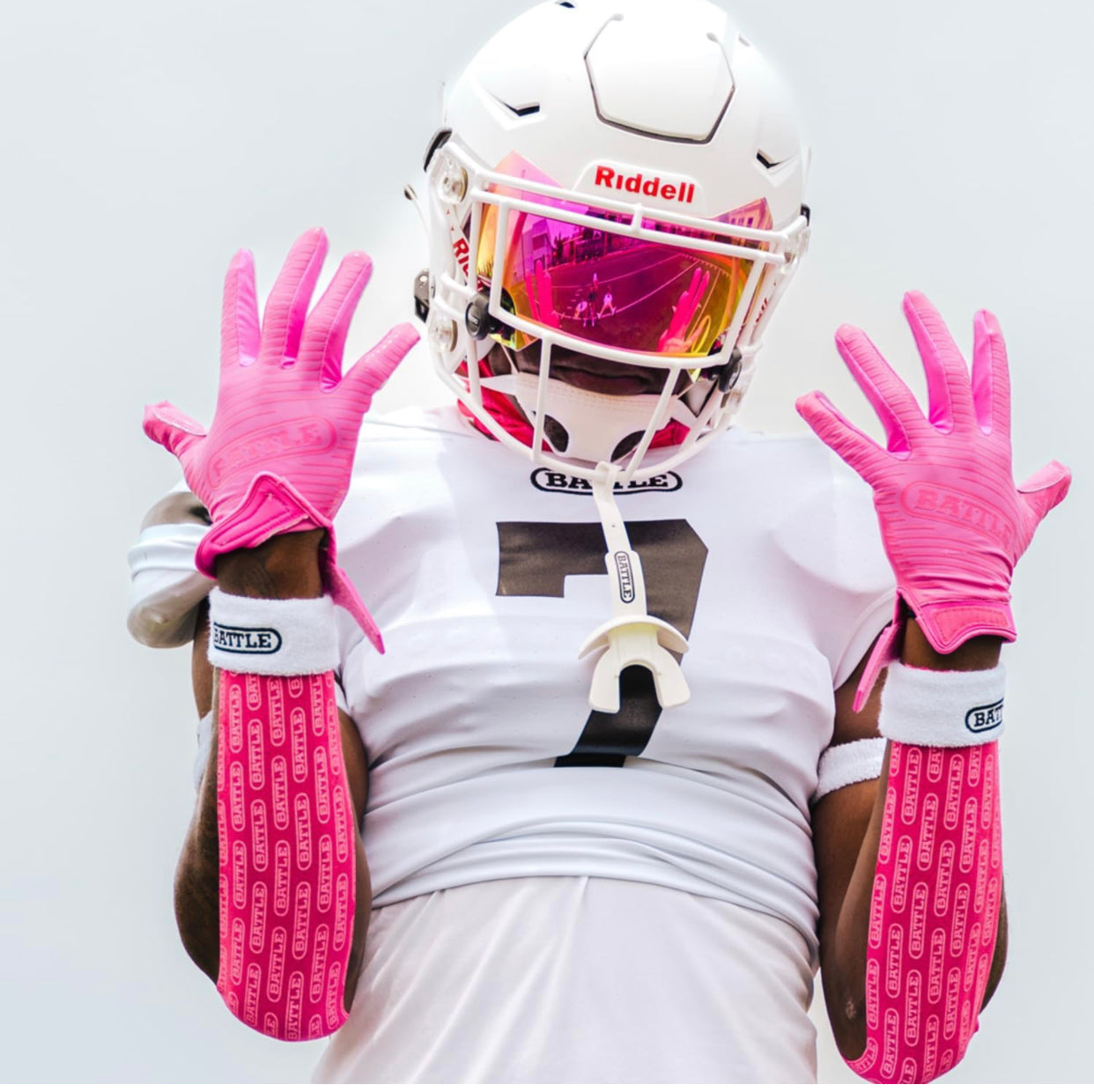 a football player wearing pink gloves and pink battle tape and a helmet