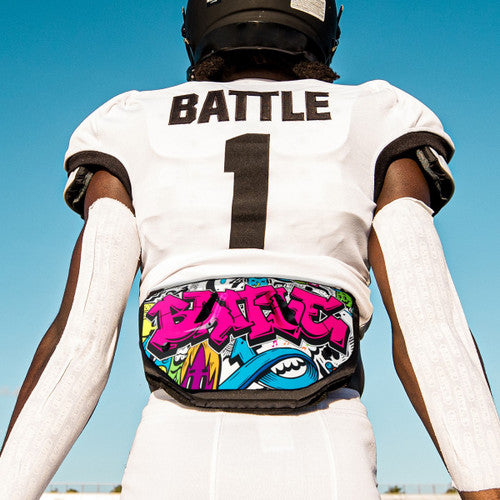 a man in a football uniform with a black Battle back plate with an image of graffiti on it with the word battle written on it in neon pink