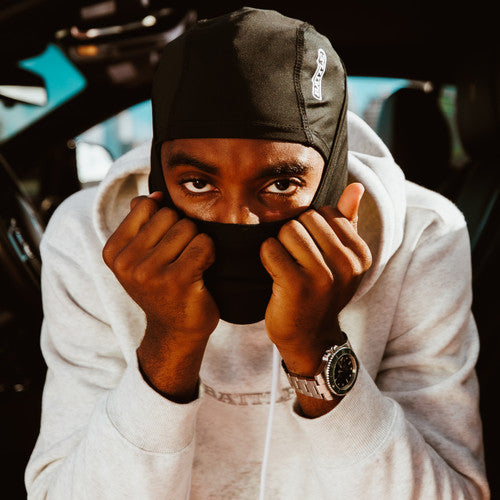 a man in a white sweatshirt wearing a black Battle performance mask covering his face